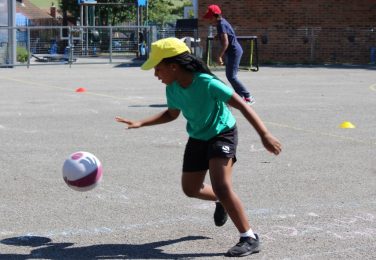 Girl pupil bouncing a ball on the KS2 playground at The Lea Primary School and Nursery