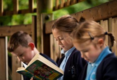 Pupils reading in the outdoor classroom at The Lea Primary School and Nursery